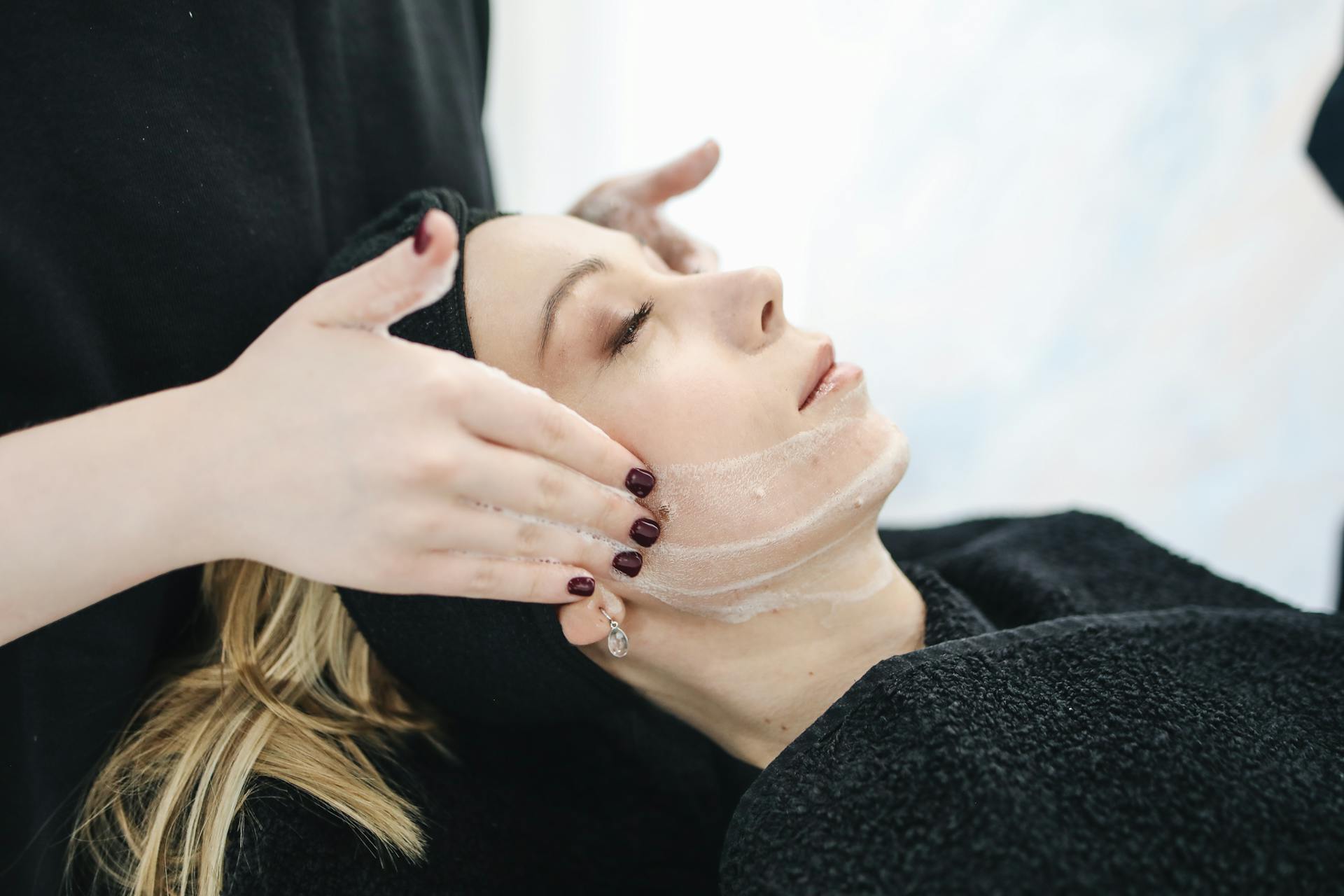 Therapist applying skincare product on client's face